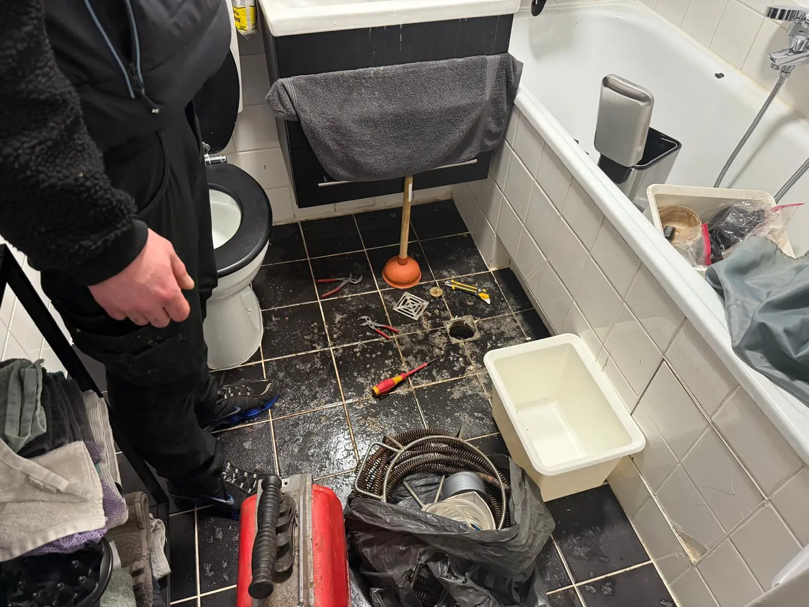 Professionelle Abflussreinigung im Badezimmer durch Facility Fix 24: Einsatz von Rohrreinigungsmaschine und Spirale bei Bodenabfluss-Verstopfung