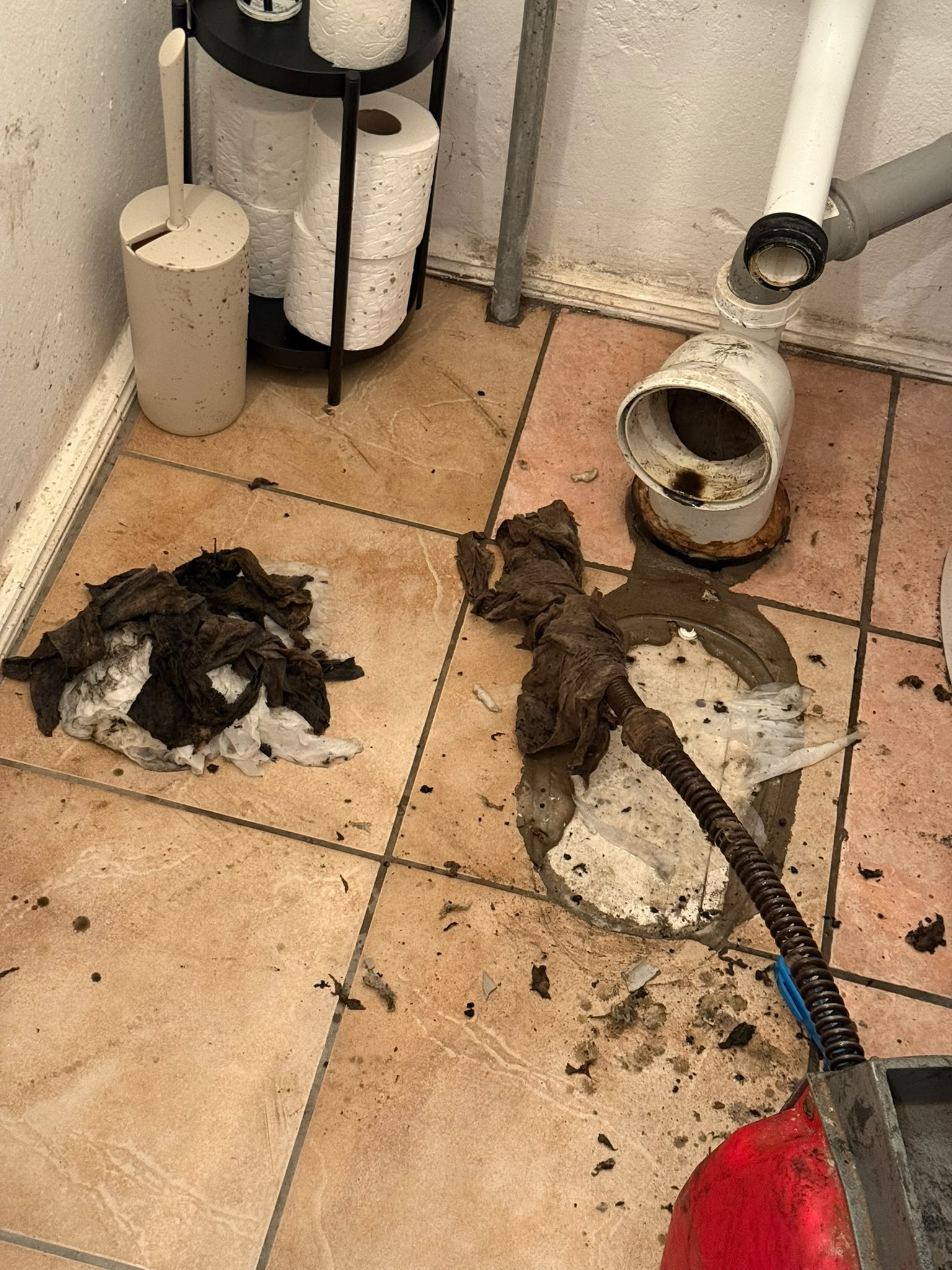 Abgebautes WC mit freigelegtem Abflussanschluss, daneben aus der Leitung entfernte Feuchttücher
