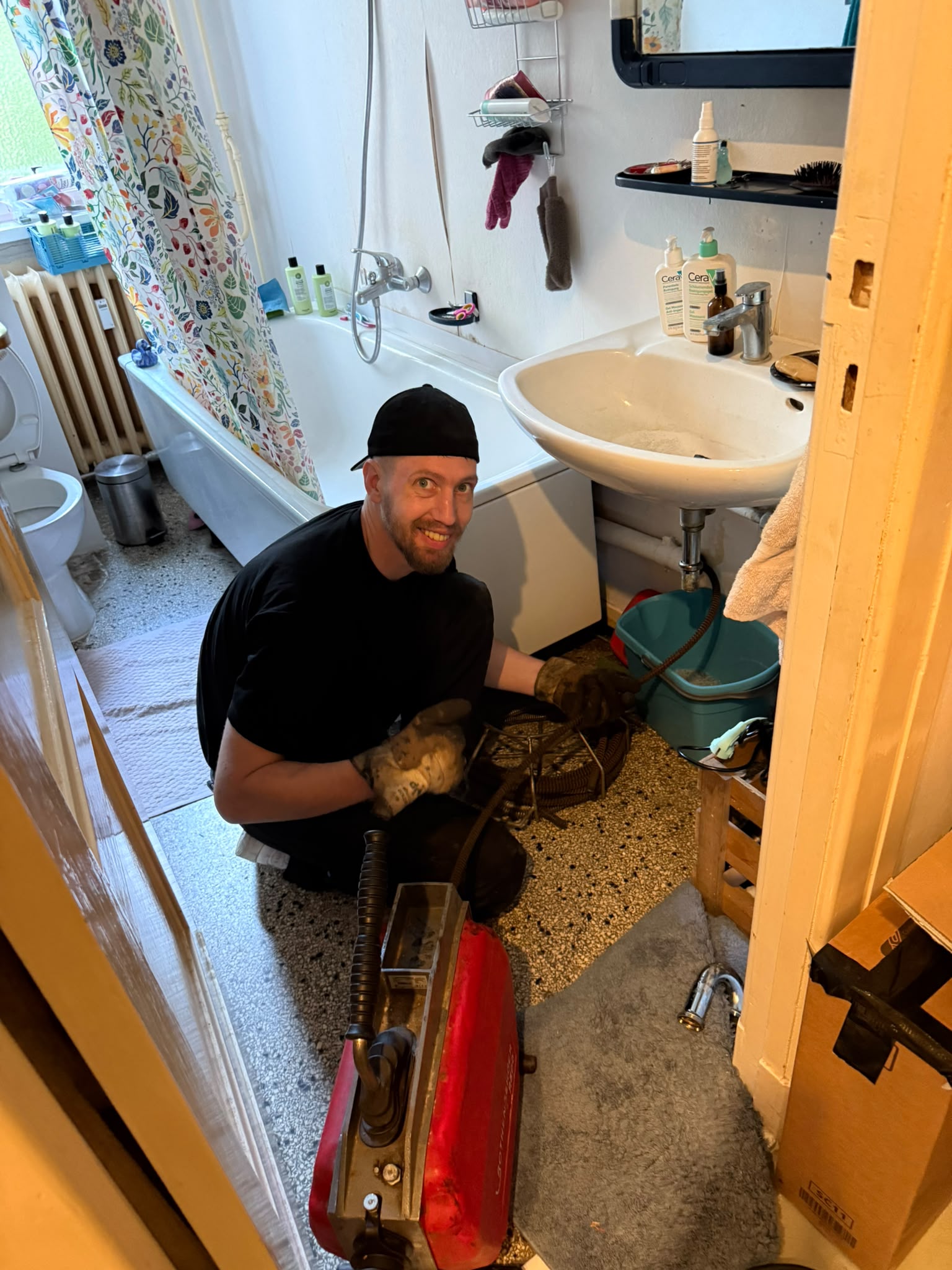 Monteur von Facility Fix 24 mit Rohrreinigungsmaschine bei einem Einsatz im Badezimmer